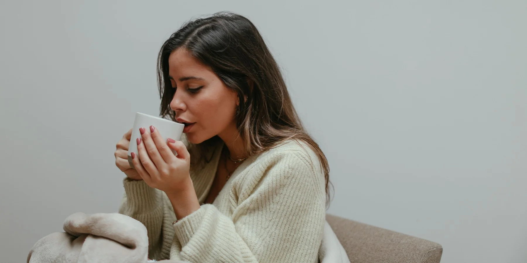 Mujer tomando té envuelta en una manta